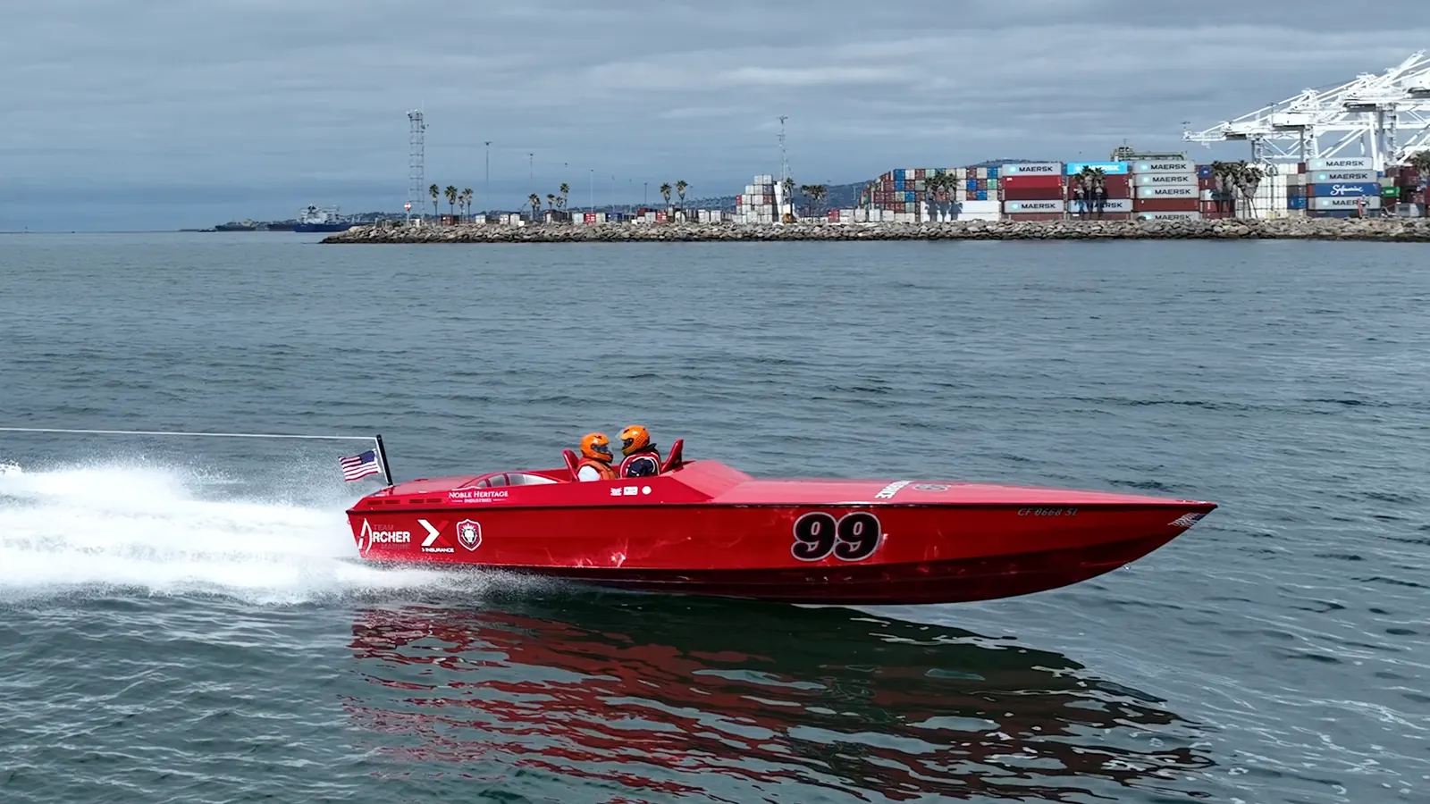 Red race boat 99 running across the channel